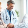 Médico de família sorridente com paciente num consultório.